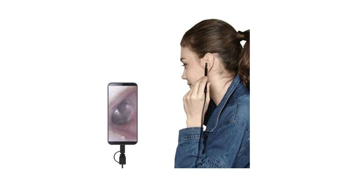 Woman holding a thin VisualCleanX camera probe at her ear, with a phone showing a lit image of the ear canal