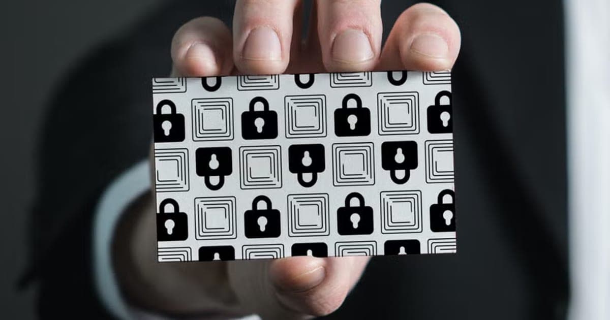 Hand holding up a Wallet Defender RFID blocking card with a black and white padlock pattern