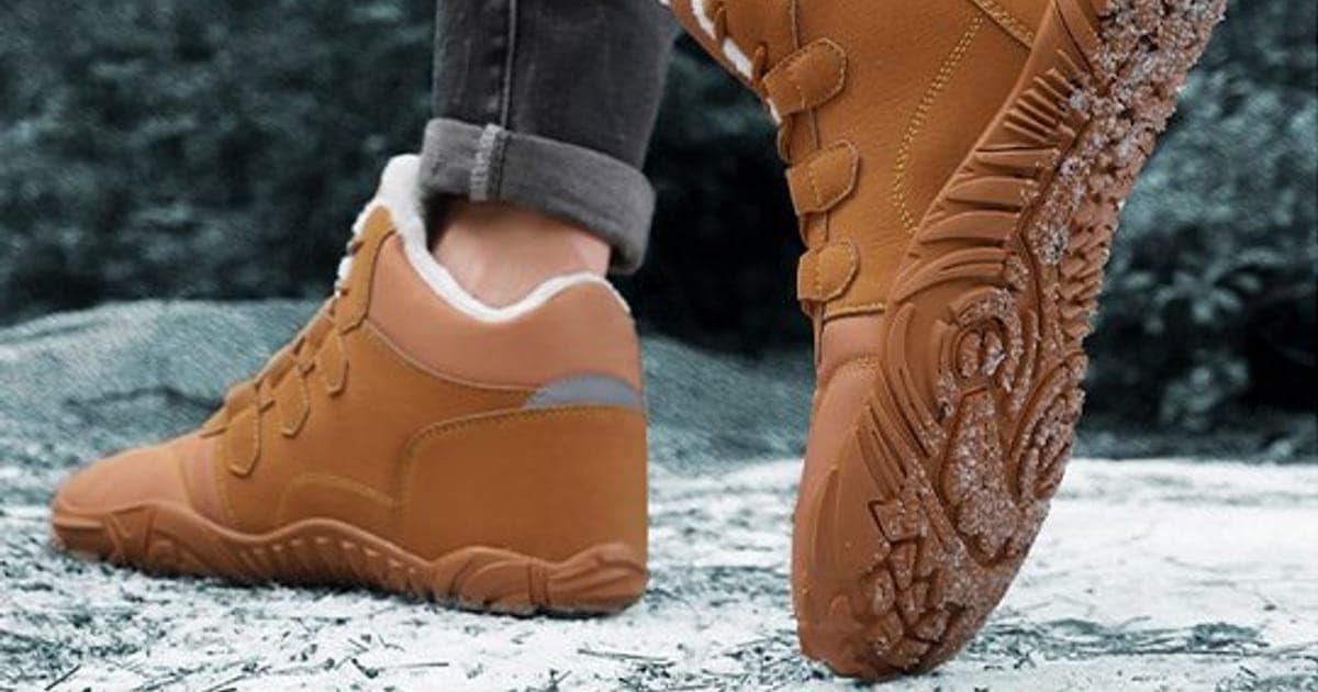 Tan WinterGlide Pro high-top boots with white fleece collars and hook-and-loop straps on snowy ground, one tilted to show a deep-lugged sole