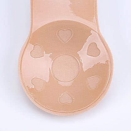 Inside of a nude Y-Bra adhesive cup with a glossy sticky surface, heart-shaped patterns and a long lift tab