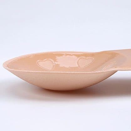 Side view of a thin nude Y-Bra silicone cup showing its shallow curve, sold as the extra light version add-on