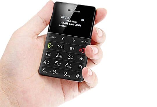 ZenPhone XS black card phone held in a hand, its small screen showing a Vodafone network name and date, above menu, OK, MP3, BT and number keys