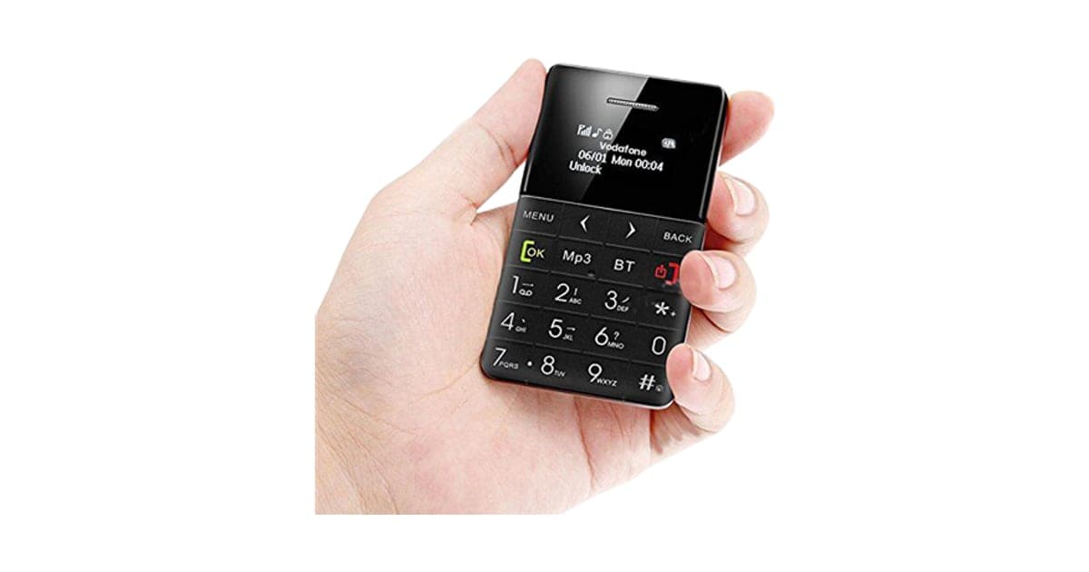 A hand holding the black ZenPhone XS credit-card-size phone with a small screen and a numeric keypad