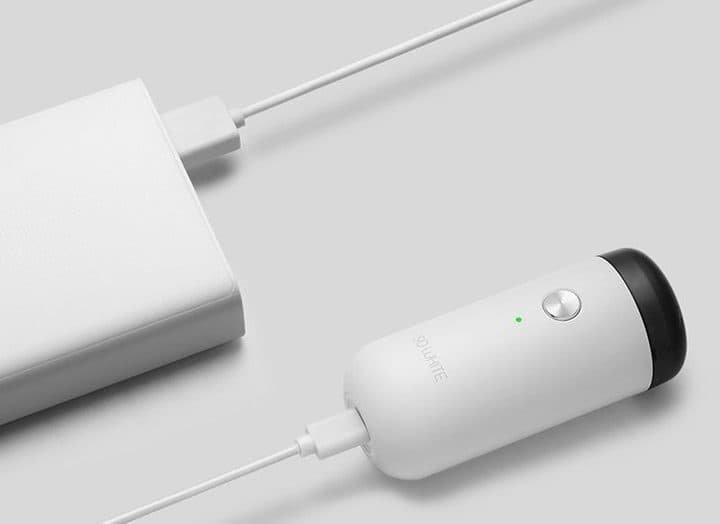 White mini shaver printed So White charging by cable from a white power bank, with a green indicator light