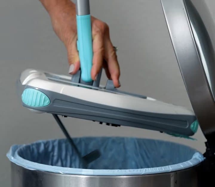 Hand holding the Zippi Sweeper over a bin with the dust hatch open