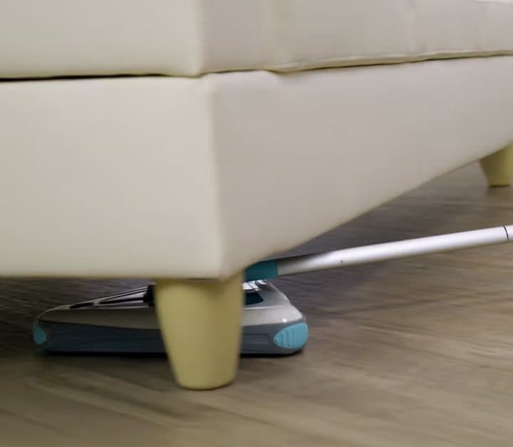 Slim Zippi Sweeper head reaching under a low sofa