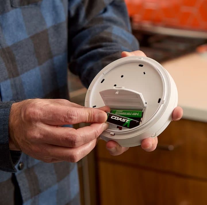 Hands putting a Zithion-X battery into a ceiling smoke alarm