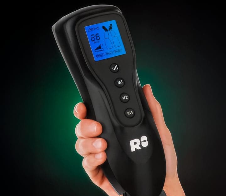Hand holding the Air-C handheld controller with its blue screen and mode and intensity buttons