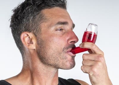 A man breathing out through the AirPhysio mouthpiece, holding the device level