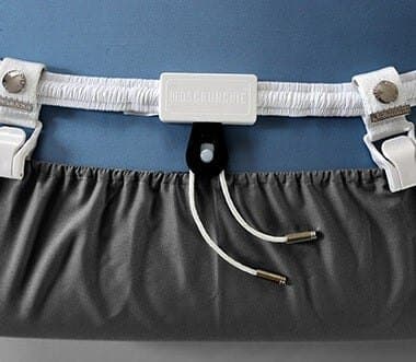 Bed Scrunchie band clipped to the hem of a grey fitted sheet with the cord hanging below