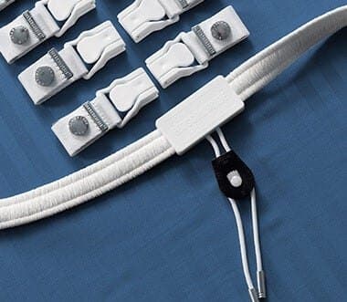 White Bed Scrunchie elastic band with its drawcord lock and a row of white sheet clips on a blue sheet