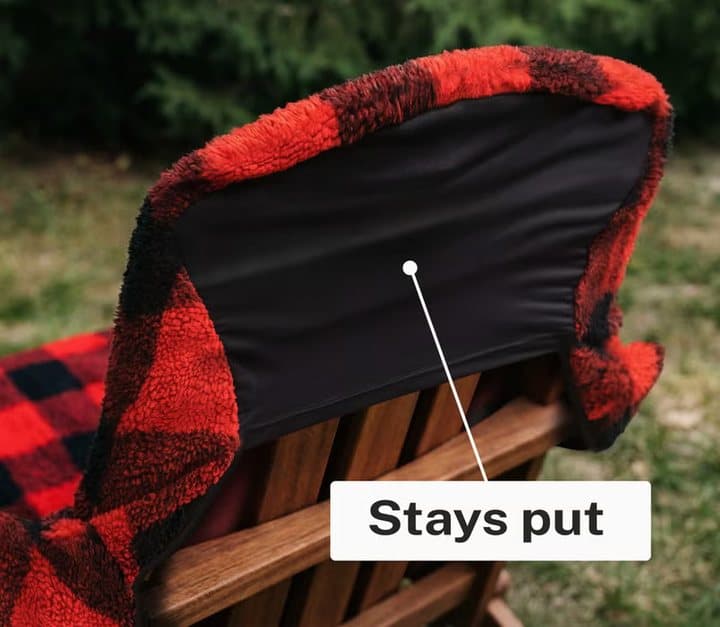 Close-up of the black stretch back of a Chair Blanket hooked over an Adirondack chair, labelled stays put