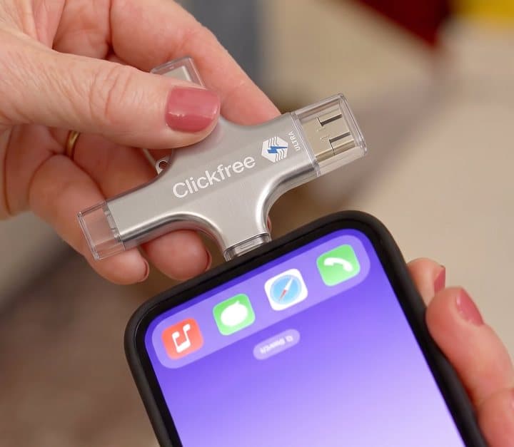 Clickfree drive plugged into the charging port of an iPhone held in a hand