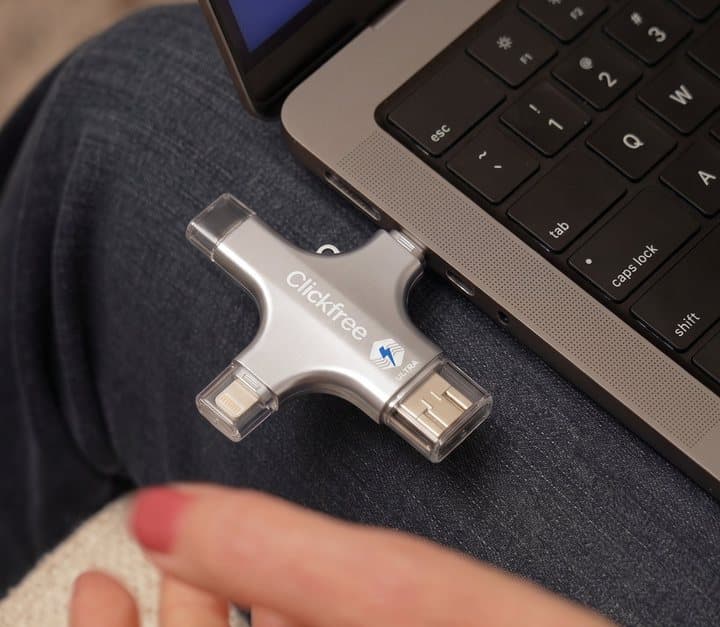 Clickfree drive plugged into the side of a laptop resting on a person's lap