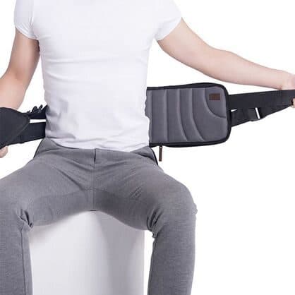 Seated man holding out the straps of a grey CorrectBack pad with raised ribbed padding on the inside