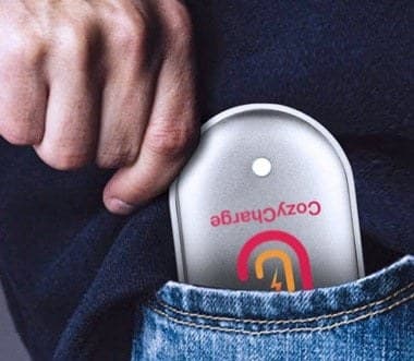 Hand sliding the silver CozyCharge into the front pocket of a pair of jeans