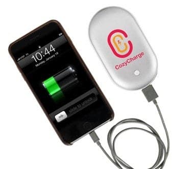 CozyCharge hand warmer connected by cable to a smartphone showing a charging battery icon