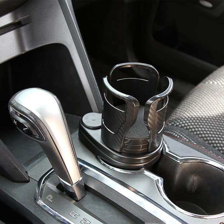 Dual CupStation with its arms closed sitting in a car cup holder next to the gear lever