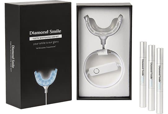 Black DiamondSmile box with a clear LED mouth tray and control unit inside, glowing blue tray on the lid and three whitening pens