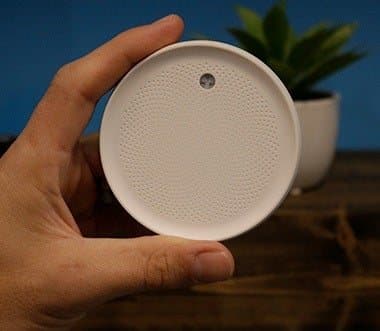Hand holding a round white Dodow sleep light to show its palm-sized scale