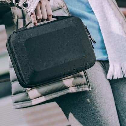 Person carrying a black hard-shell zip case with a handle