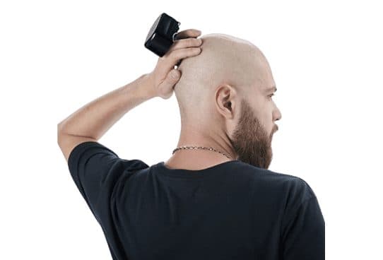 Man in a black T-shirt seen from behind, shaving the back of his bald head with a compact black ElectricShaver Pro