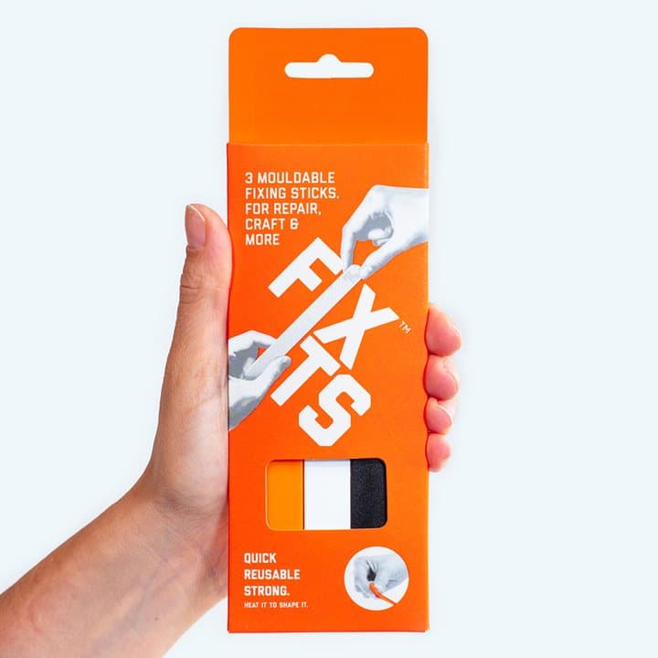 Hand holding an orange FixIts pack labelled three mouldable fixing sticks for repair, craft and more