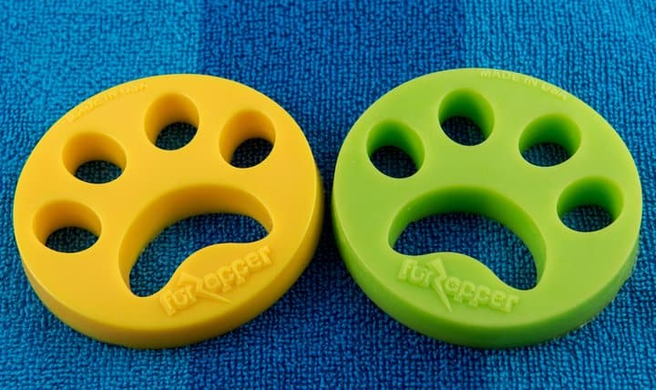 Yellow and green FurZapper silicone discs on a blue towel