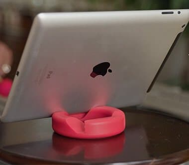Silver iPad standing in landscape on a red GoDonut on a wooden table