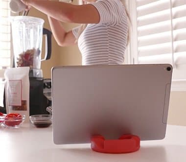 Tablet standing on a red GoDonut on a kitchen counter next to a blender