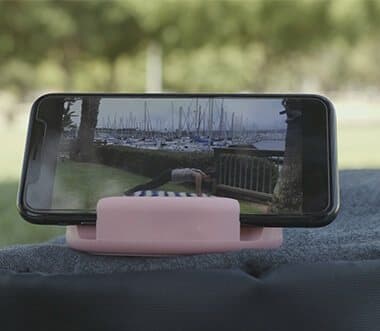 Phone in landscape on a pink GoDonut outdoors with water in the background