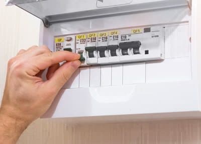 Hand switching off a circuit breaker in a consumer unit before installing GuideLight