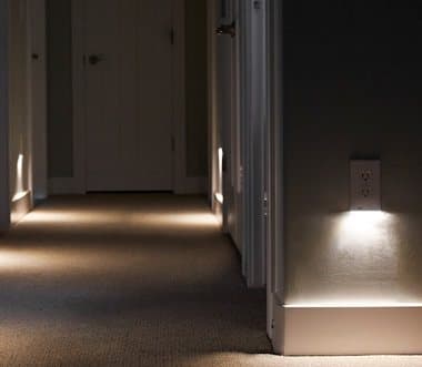 Dark hallway lit by a GuideLight outlet cover casting a pool of light on the floor