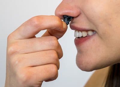 Woman inserting a Hale nasal dilator into her nostril