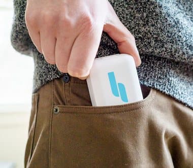 Hand slipping a small white Hale carry case into a trouser pocket