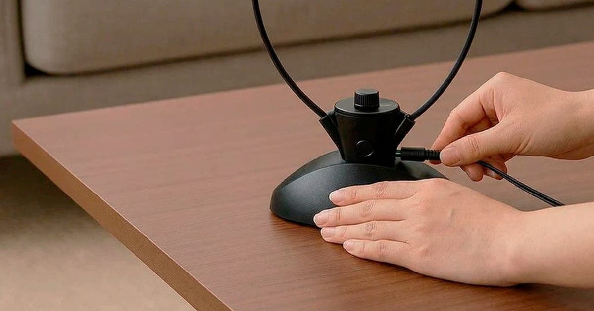 HearDirect under-chin wireless TV headset standing on its round black charging cradle on a living room table