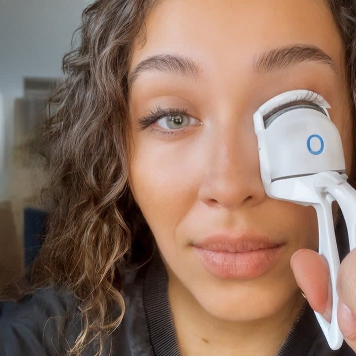 Woman using the Bime Beauty heated eyelash curler on her upper lashes