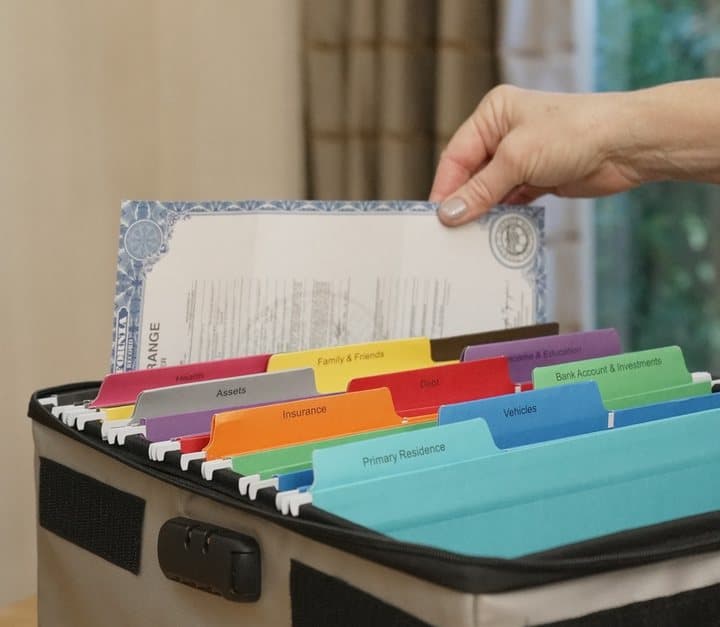 Hand lifting a certificate from colourful labelled hanging folders inside the open ICE Box case