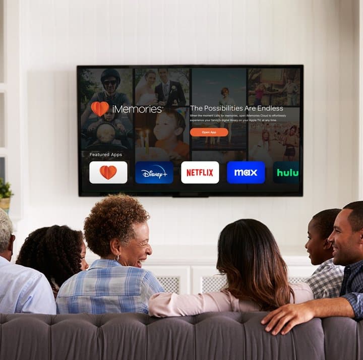 Family on a sofa watching digitized home movies on a large TV through the iMemories app