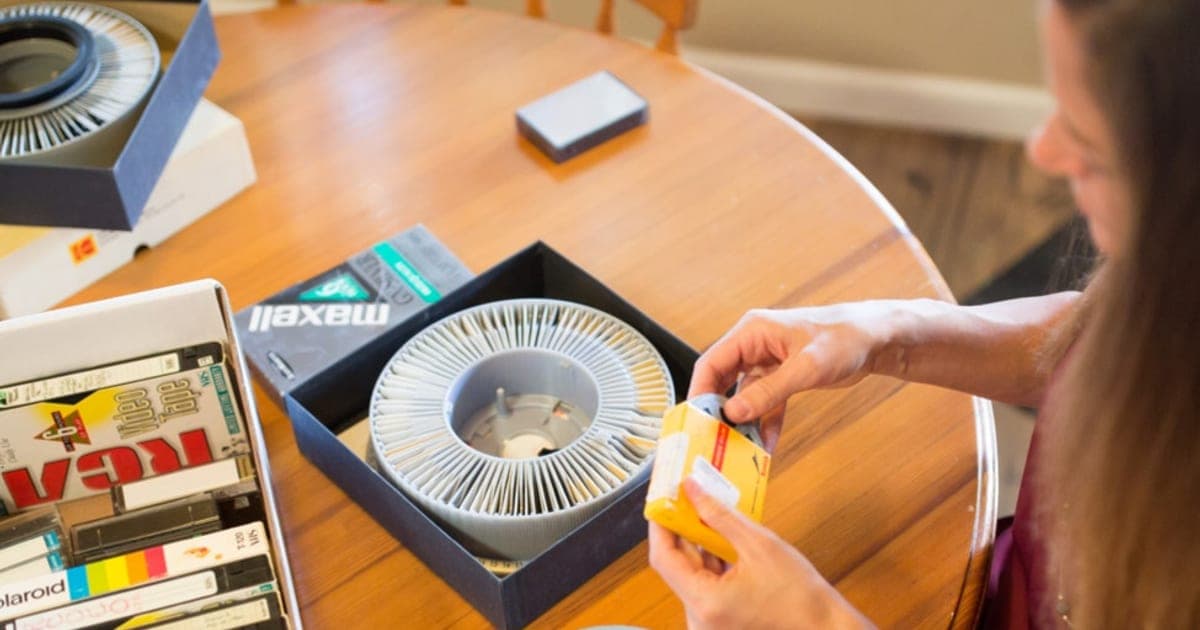 Woman packing old film reels, videotapes and slides into an iMemories SafeShip box on a kitchen table