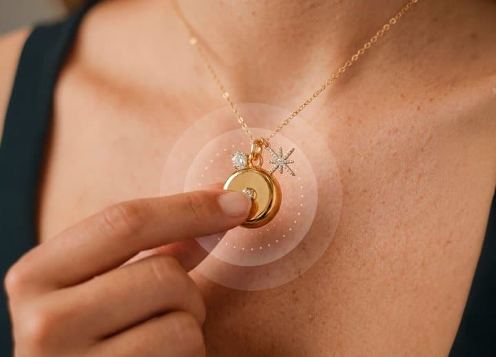 Woman pressing the back of her gold invisaWear necklace charm between finger and thumb