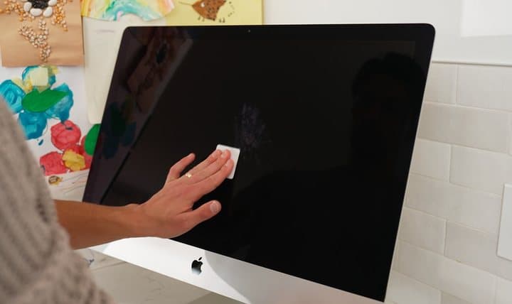 Hand wiping a large computer screen with a Jiffys pad