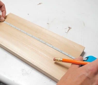 Kelvin 17's flexible tape measure pulled along a wooden board while a pencil marks it