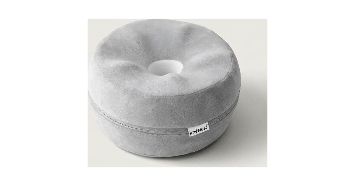 Grey doughnut-shaped knēNest knee pillow with a hollow centre and a small brand tag