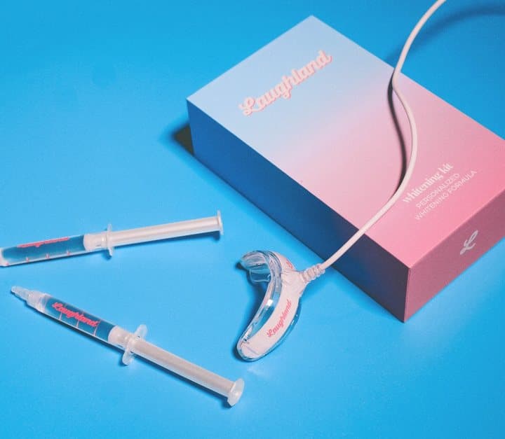 Pink and blue Laughland box with a gel syringe and white LED mouthpiece on a blue background