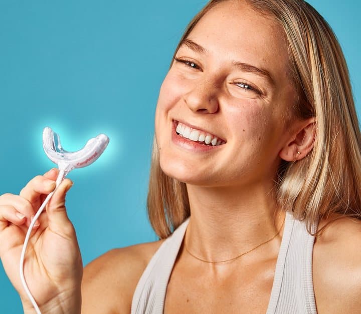 Smiling woman holding the Laughland LED mouthpiece glowing blue