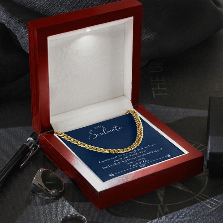Gold-tone Luxury Cuban Link chain in an open mahogany-style box with a small light in the lid, beside a pen and a signet ring