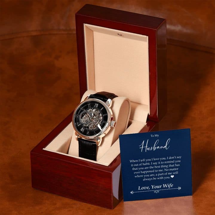 Rose gold-tone Luxury Open Watch in a mahogany-style box on a tan leather sofa, with the To My Husband card leaning against the box