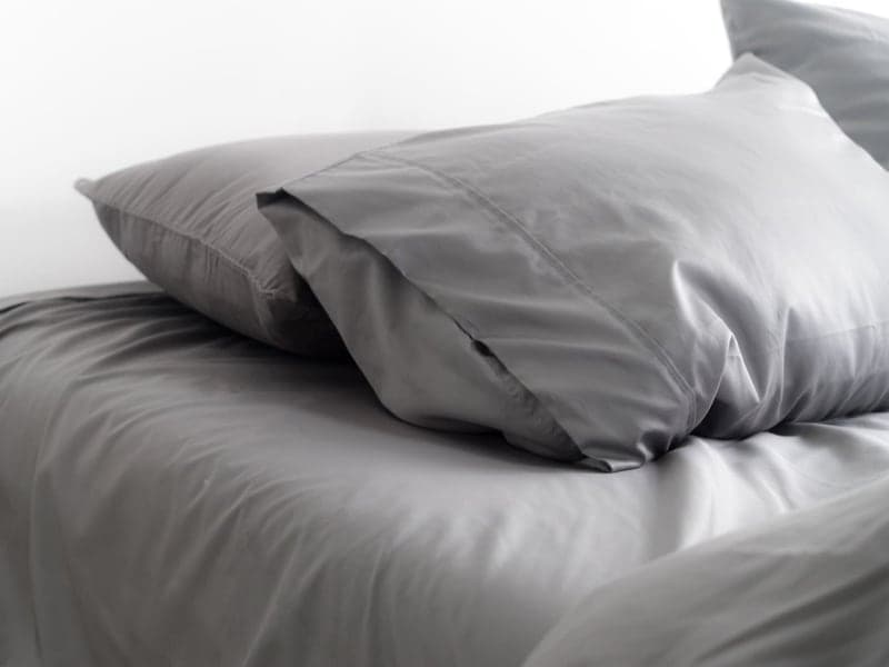 Close view of grey Miracle Made pillowcases on a bed, showing the sateen sheen of the cotton