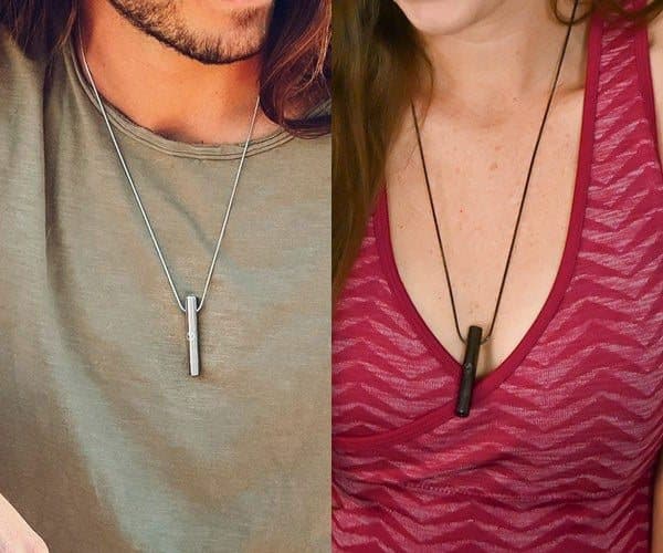 A man and a woman each wearing a Moksha Beam pendant on a chain over a T-shirt